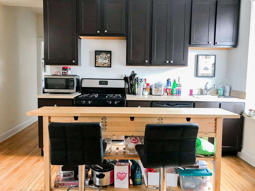 a kitchen with black cabinets and a wooden island with black chairs