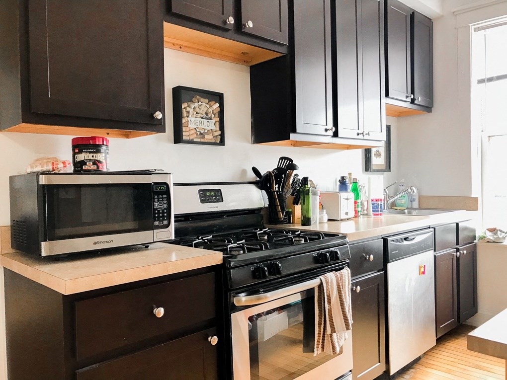 a kitchen with black appliances and white cabinets and wood floors