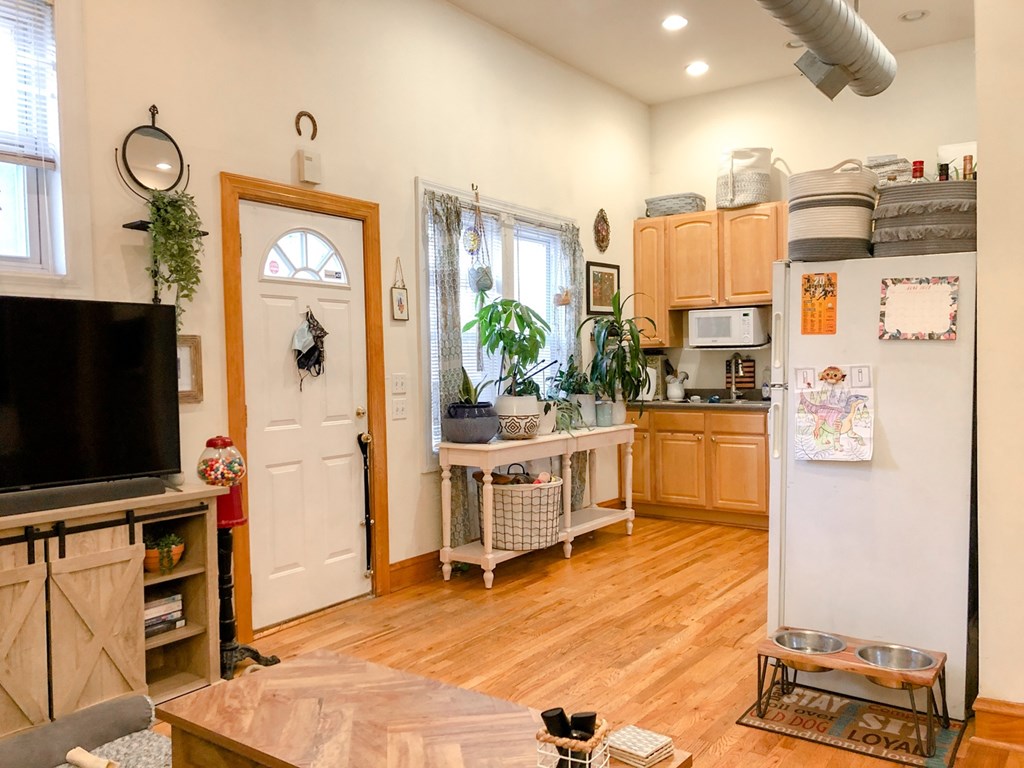 A kitchen with a white fridge and wooden floors.