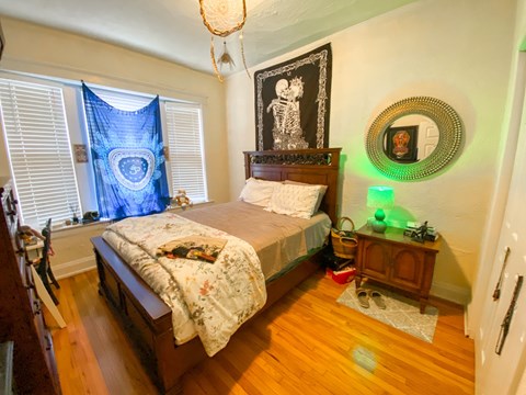 A bedroom with a bed, a dresser, and a mirror.