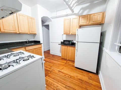 A kitchen with a white stove and a white refrigerator.