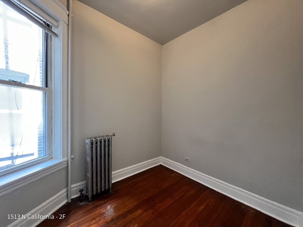 room of an empty room with wooden floors and a radiator