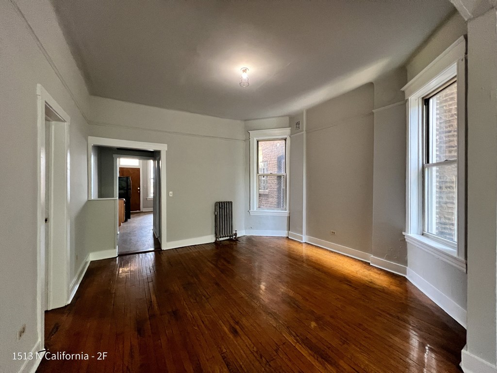 an empty living room with wood floors and a radiator