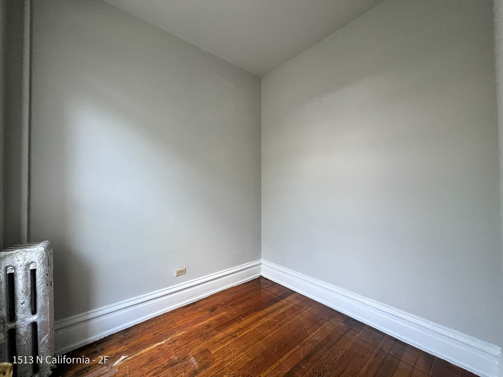 the corner of a room with white walls and wooden floors