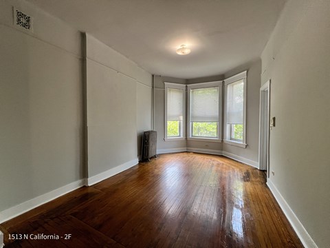 ?? bedroom with hard wood flooring and three windows