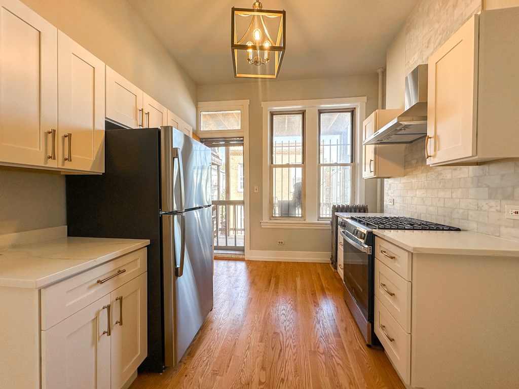 A kitchen with black appliances and wooden floors.