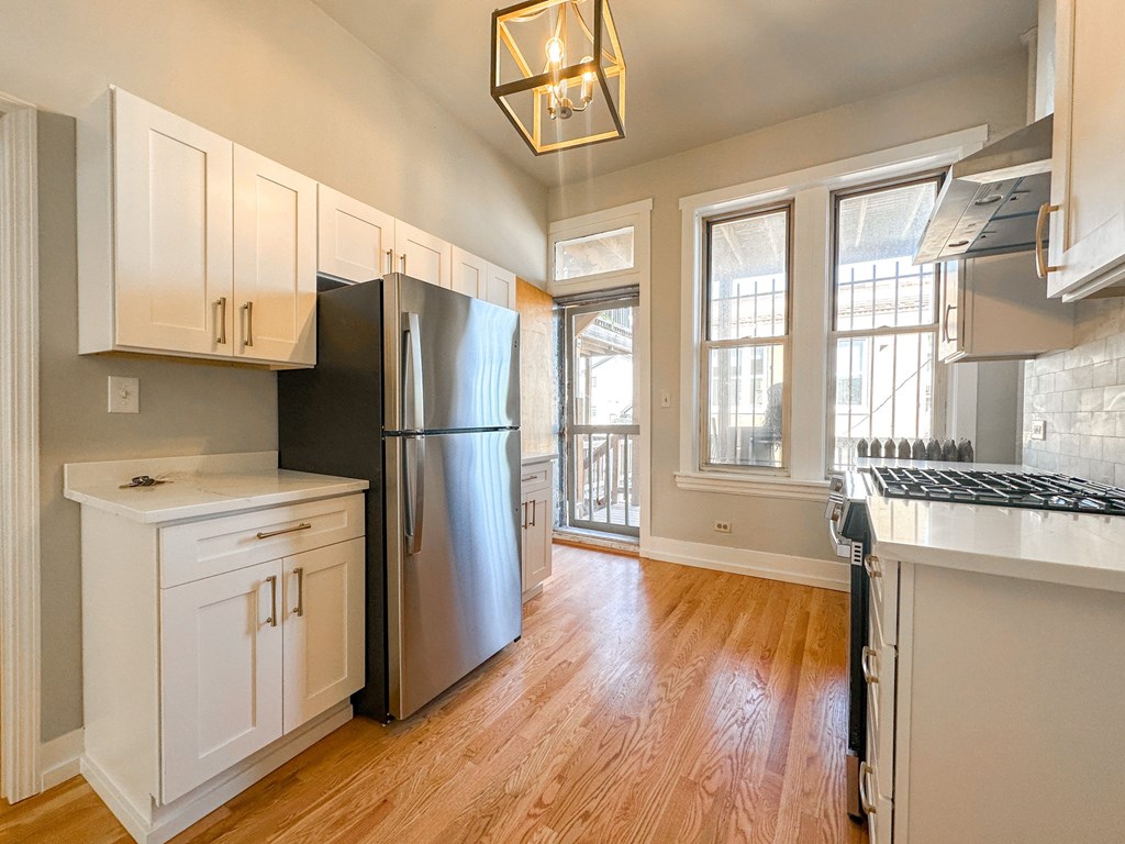 A kitchen with a black fridge and white cabinets.