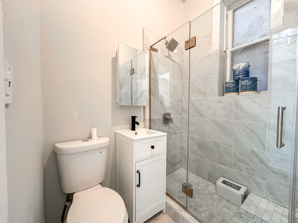 A white toilet sits next to a white cabinet in a bathroom.
