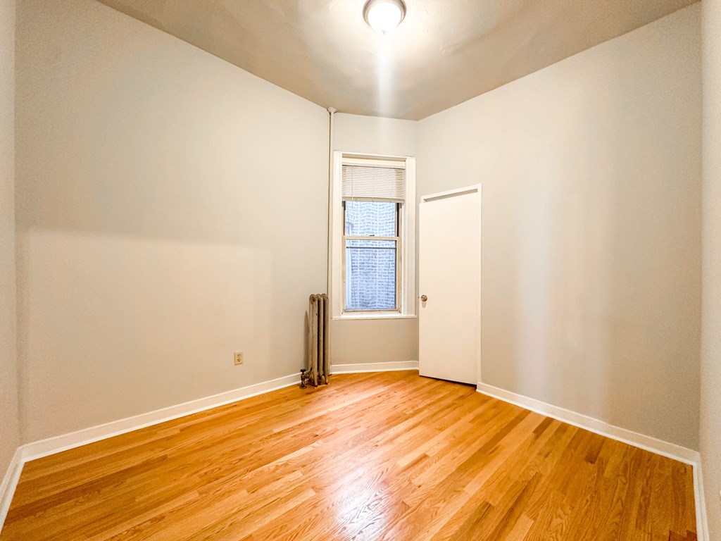 A room with wooden floors and a window with blinds.