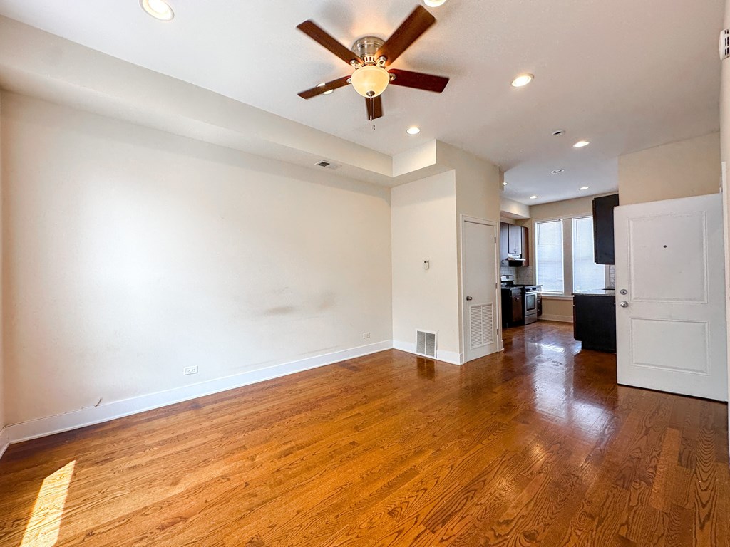 A room with a ceiling fan and wooden floors.