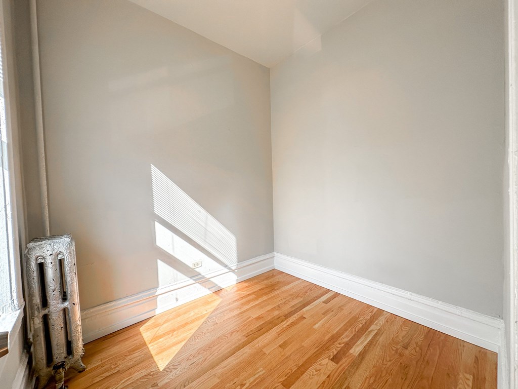 A room with wooden floors and a window letting in sunlight.
