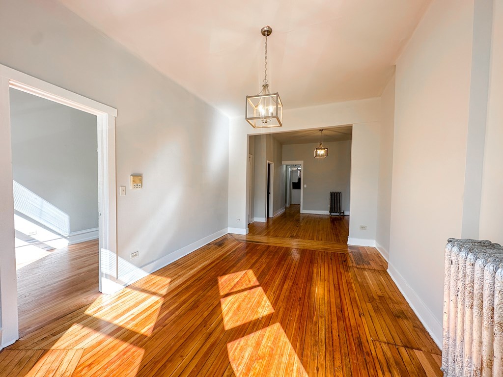 A room with wooden floors and a chandelier hanging from the ceiling.