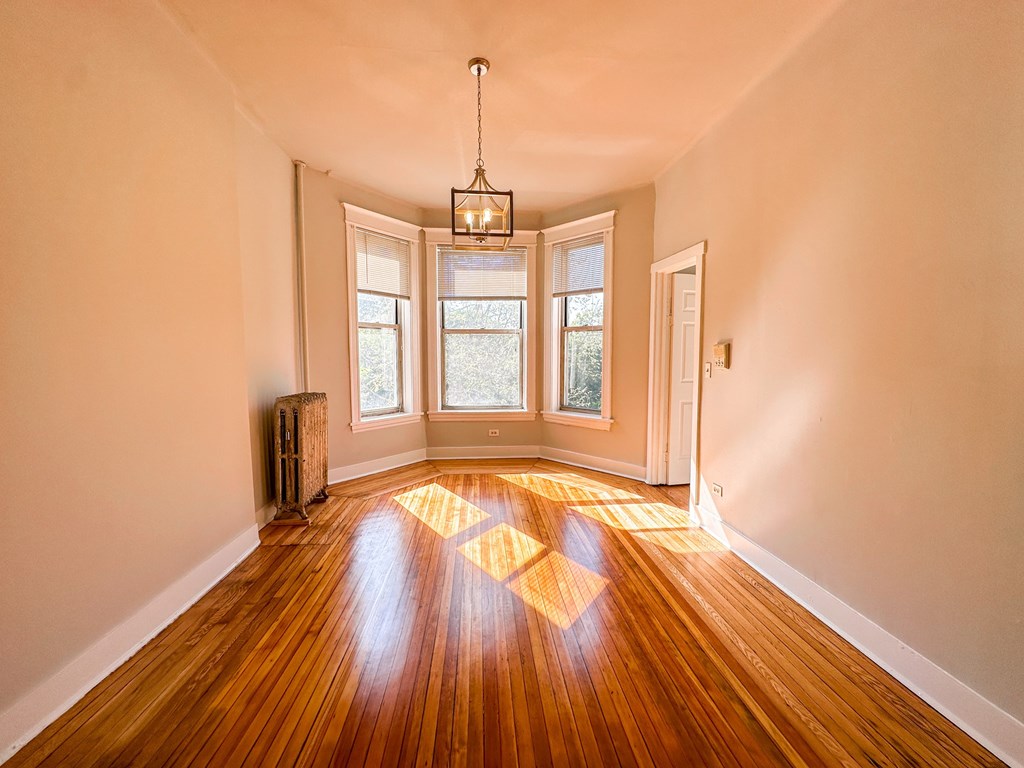 A room with wooden floors and a chandelier hanging from the ceiling.