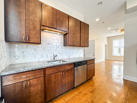A kitchen with wooden cabinets and a marble backsplash.