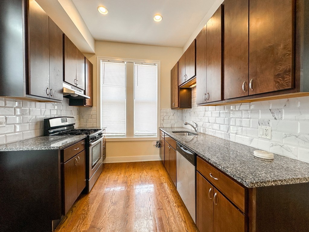 A kitchen with dark wood cabinets and a granite countertop.