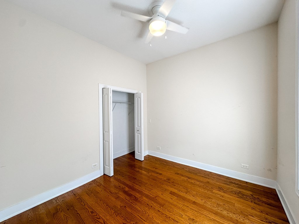 A room with a ceiling fan and wooden flooring.