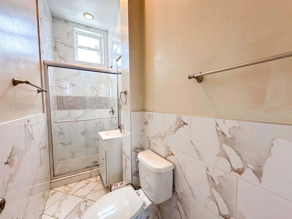 A white toilet in a marble tiled bathroom.