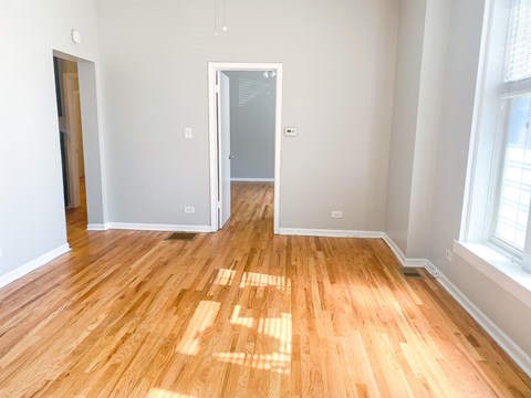 A room with wooden flooring and a doorway leading to another room.