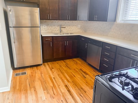 A kitchen with a stainless steel refrigerator and wooden floors.