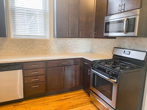 A kitchen with a black stove top oven and a black microwave above it.