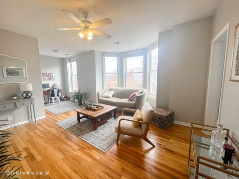 A living room with a wooden floor and a ceiling fan.