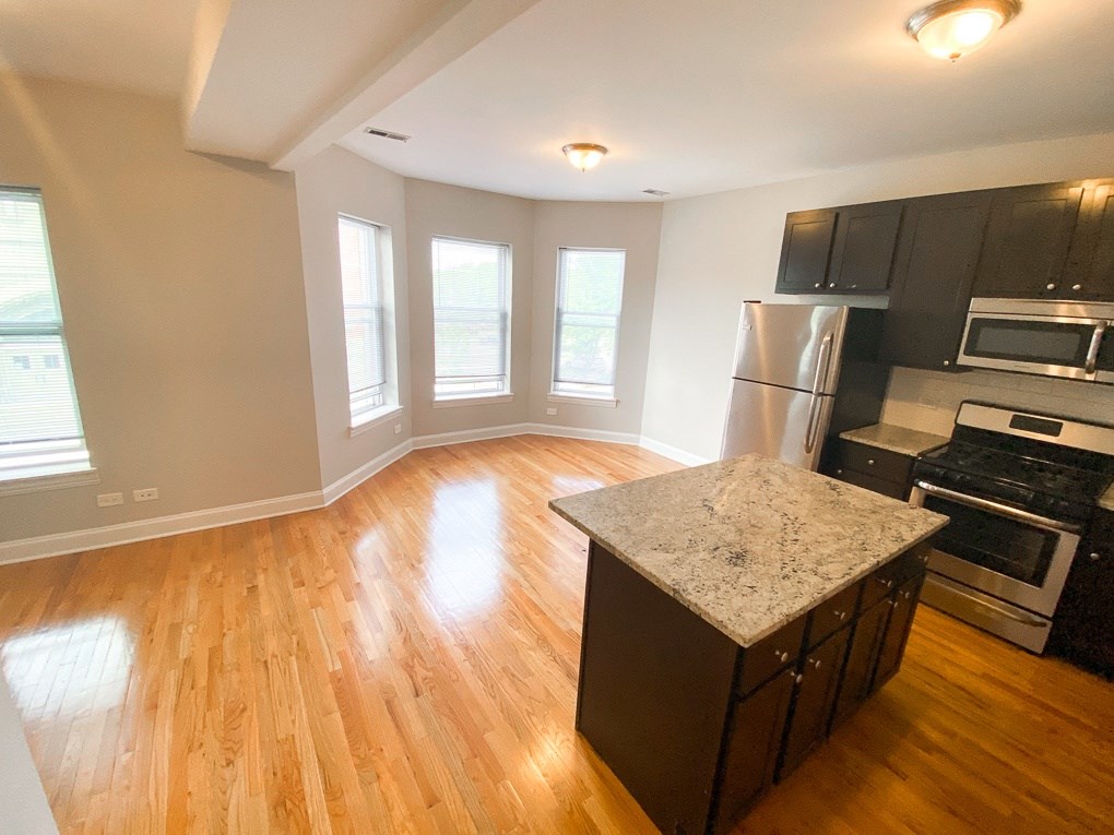 an empty kitchen and living room with a hardwood floor and