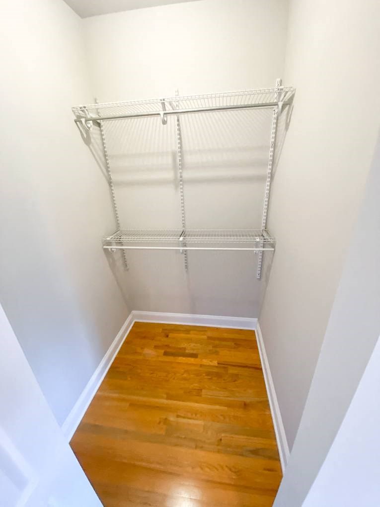 a walk in closet with a wood floor and a wire rack