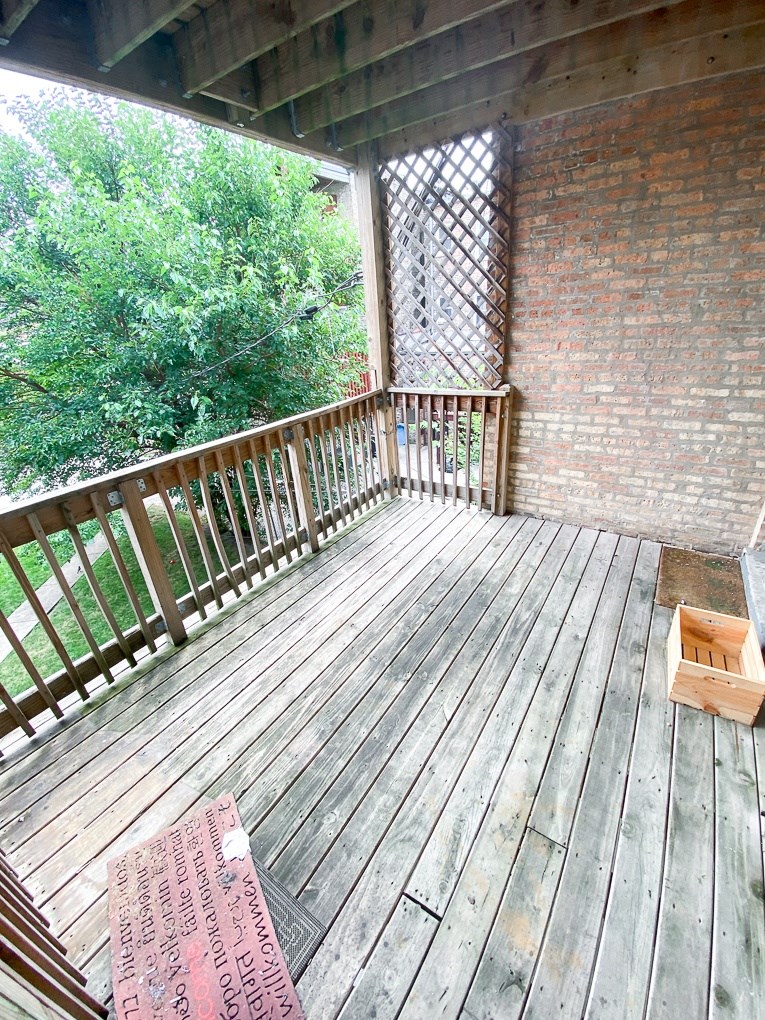 a balcony with a wooden floor and a brick wall