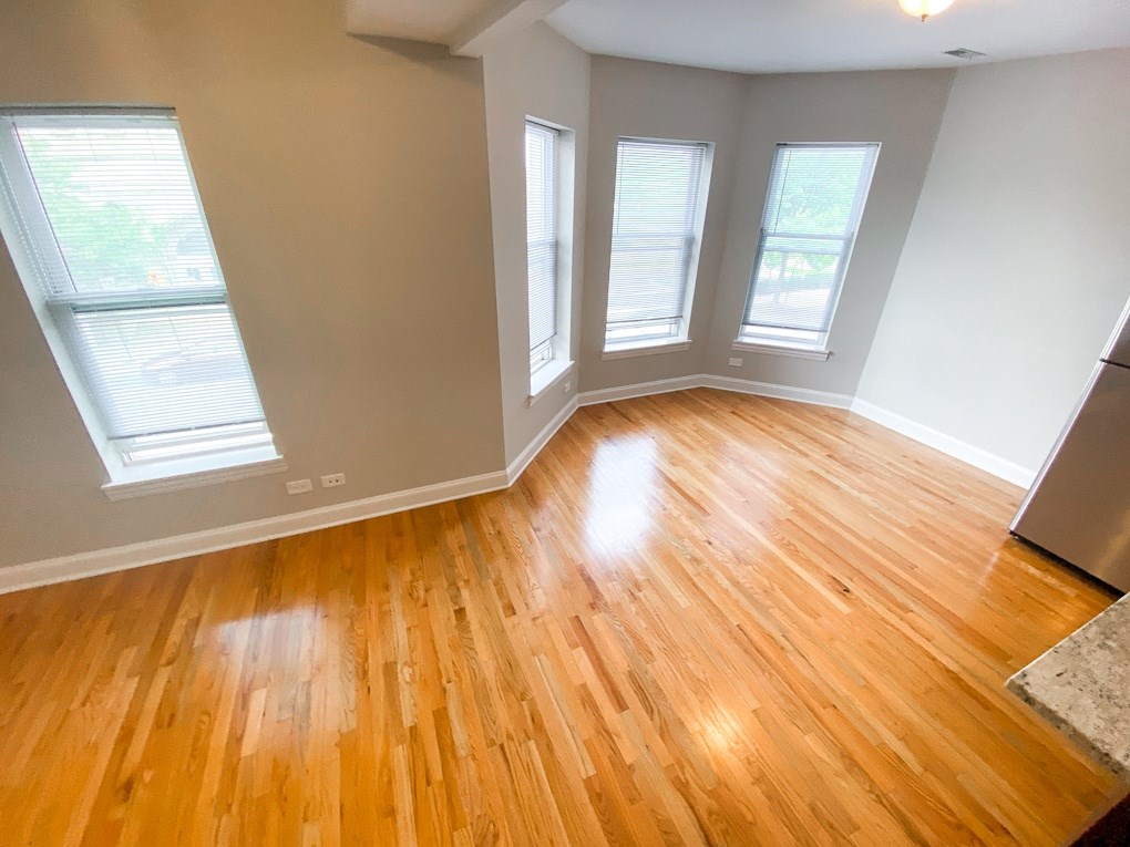 an empty living room with wooden floors and windows