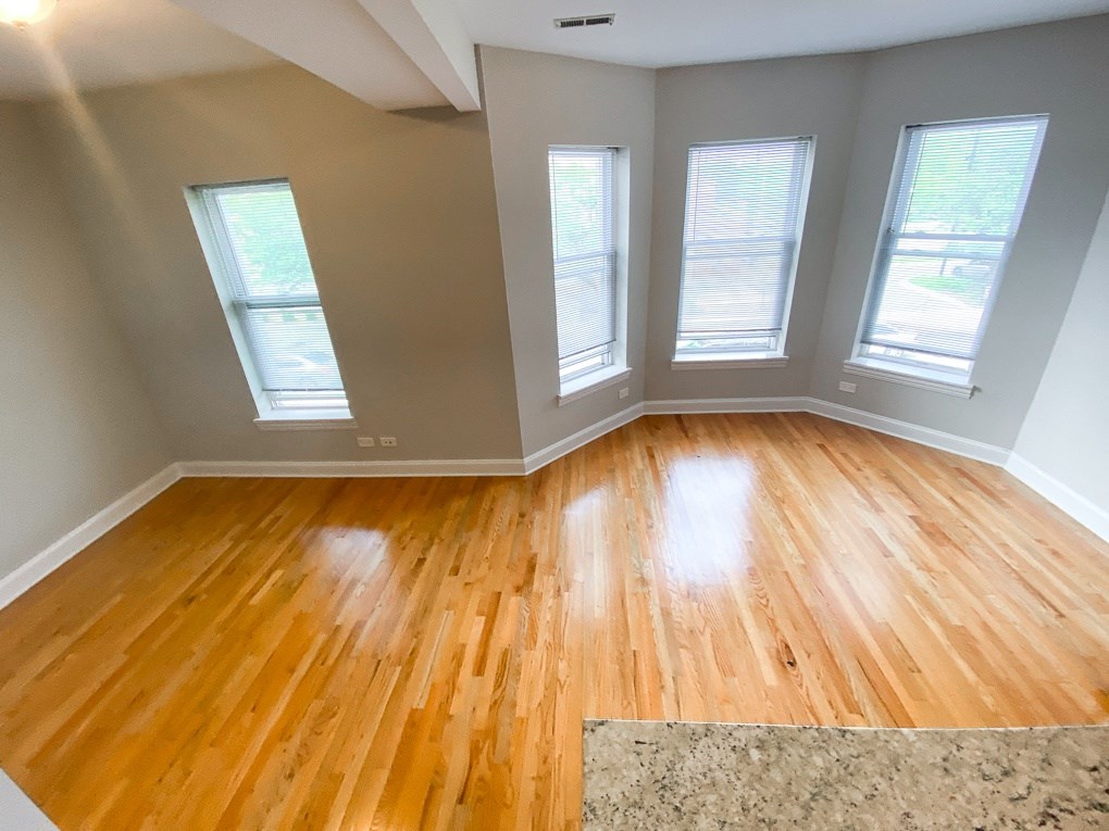 an empty living room with wooden floors and three windows