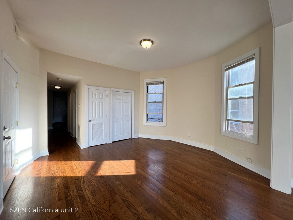 an empty living room with wood floors and white walls