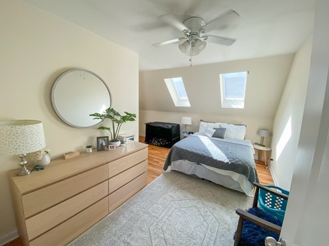 A bedroom with a bed, dresser, and ceiling fan.