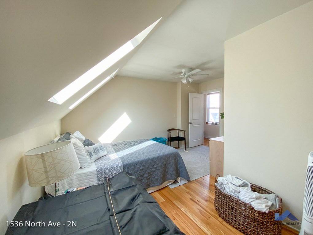 a bedroom with a bed and a ceiling fan and a door to a bathroom