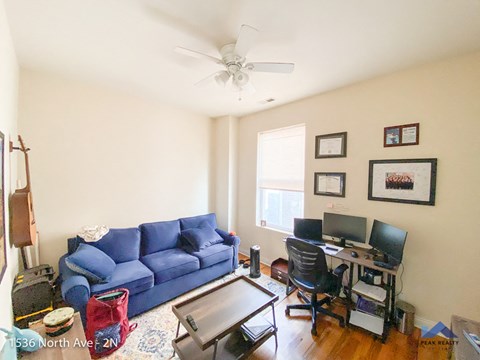 a living room with a blue couch and a desk with a computer