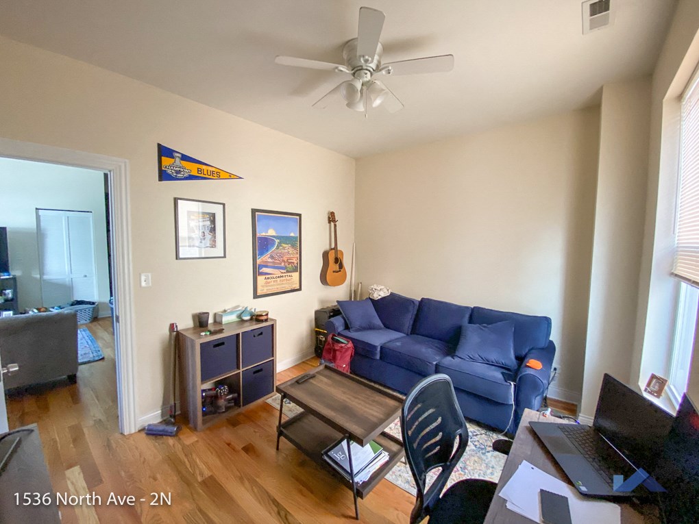 a living room with a blue couch and a ceiling fan
