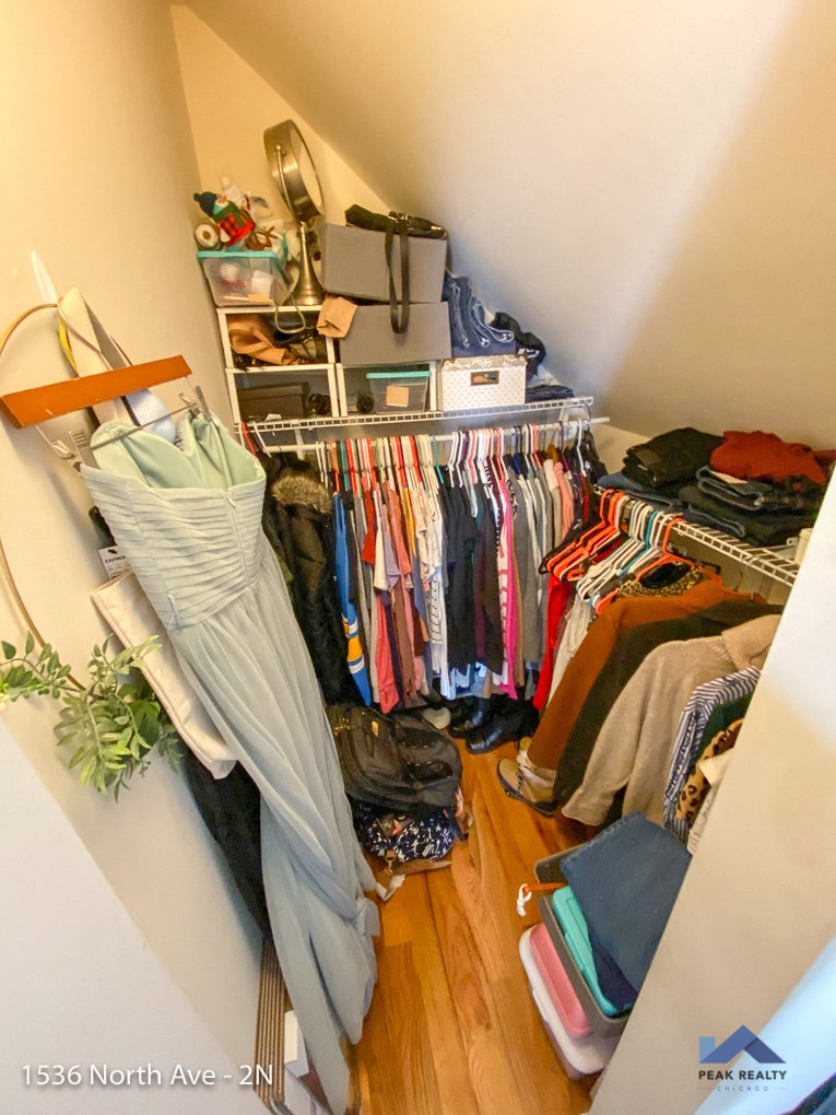 a small closet filled with clothes and a rack of clothes in it