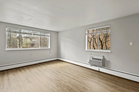 A room with a window showing trees outside and a wall-mounted air conditioner.