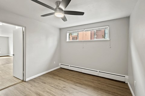 A room with a ceiling fan and a window with blinds.