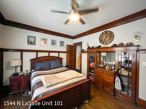 A bedroom with a bed, dresser, and ceiling fan.