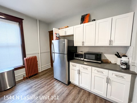 A kitchen with white cabinets and a stainless steel refrigerator.