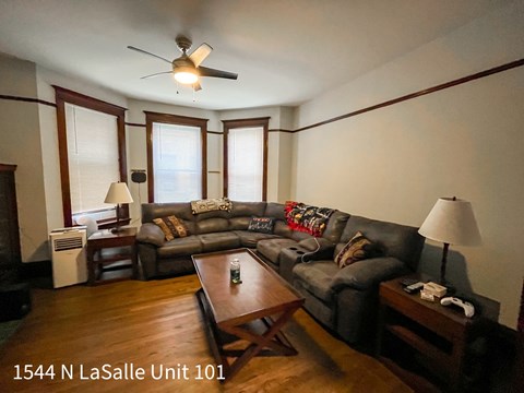 A living room with a couch, a coffee table, and a ceiling fan.