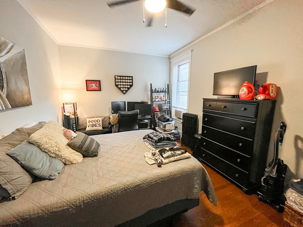 A bedroom with a bed, dresser, and ceiling fan.