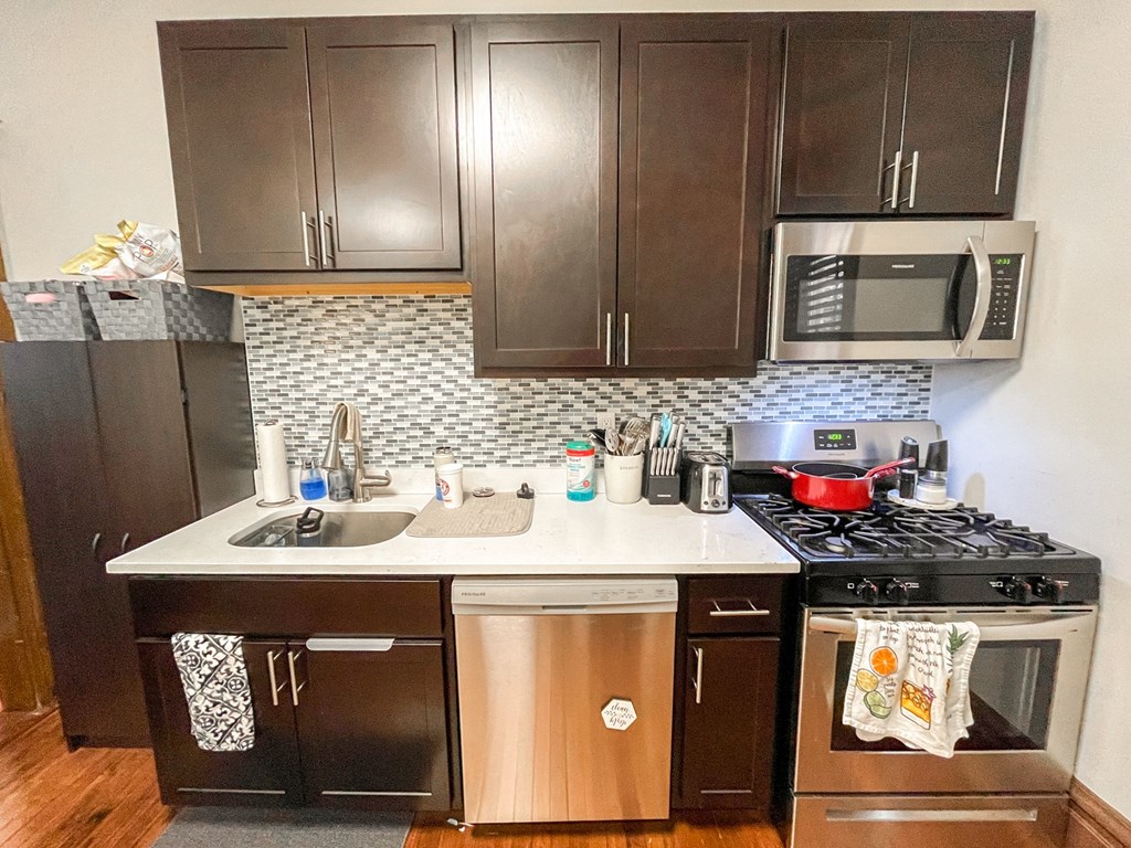 A kitchen with a black refrigerator, a black stove, and a black microwave.