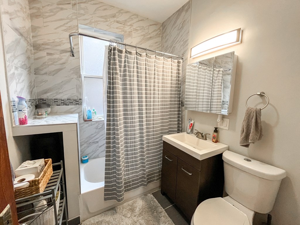 A bathroom with a white toilet, a sink, and a shower curtain.