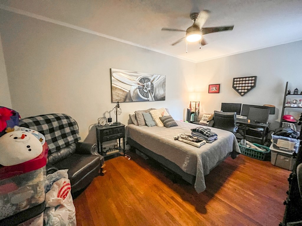 A bedroom with a bed, a couch, and a ceiling fan.