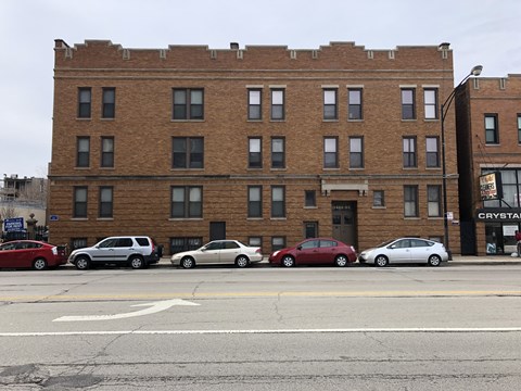 A red car is parked in front of a brick building.