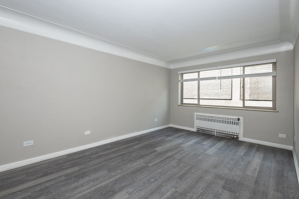 an empty room with a radiator and a large window