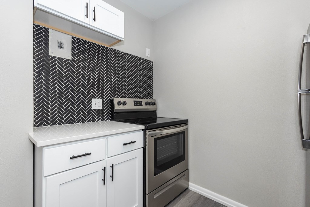 a kitchen with white cabinets and black and white tile
