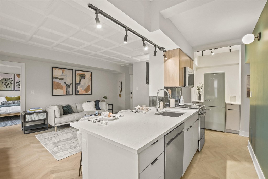 a white kitchen with an island and a living room