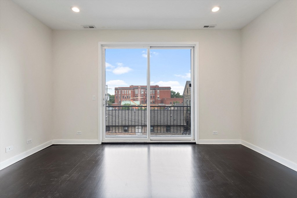 a bedroom with a large window and hardwood floors